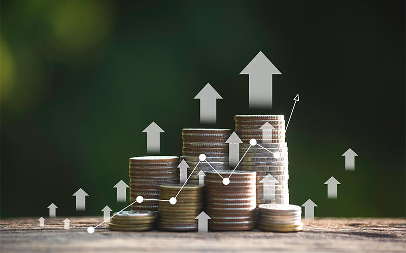 Stacks of coins with upward arrows symbolize financial investment growth.
