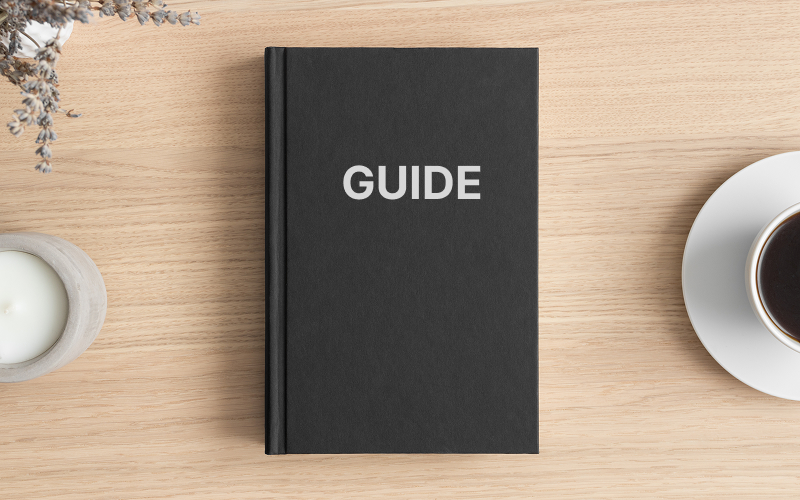 Top view of black book labeled GUIDE on wooden desk.